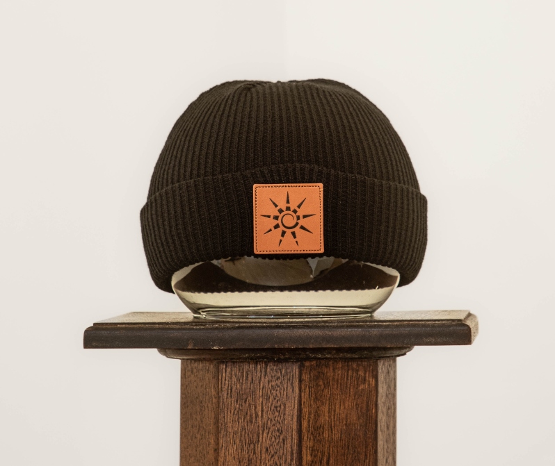 Product Description: Black acrylic beanie with a square leather patch featuring HAC sun logo in black.</br> HAC Beanie with Leather Patch